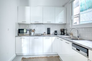 A modern kitchen with white cabinets, a microwave, a coffee maker, and a dishwasher. - SMG Boutique Apartment (Athina)