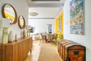 A modern living room with a wooden console, a dining area with a table and chairs, and a large painting on the wall. - SMG Boutique Apartment (Athina)