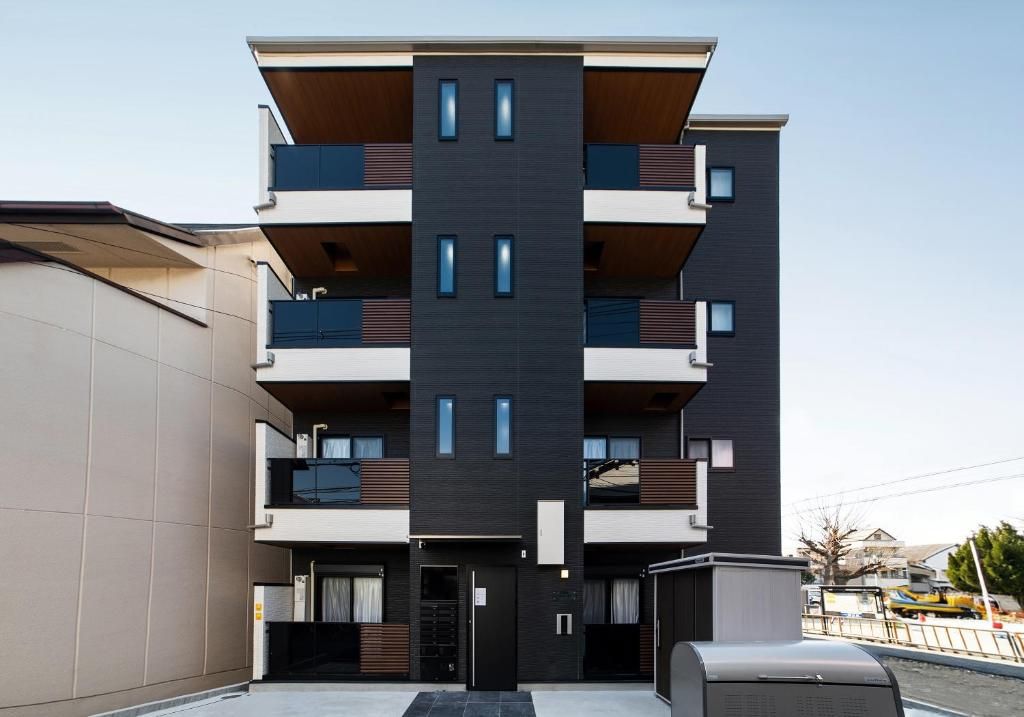 A multi-story residential building with balconies, a central entrance, and a parking area.