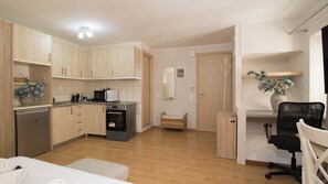 A compact kitchen with a microwave, oven, and refrigerator. There is a dining area with a table and chairs. - Alto Studio by CorfuEscapes (Kerkira)