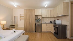 A compact hotel room with a bed, bedside table, lamp, and a kitchenette with a microwave, toaster, and refrigerator. - Alto Studio by CorfuEscapes (Kerkira)
