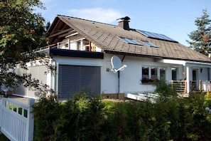 A house with a sloped roof, solar panels, a garage, and a covered porch area. - Cuckoo House Premium (Titisee-Neustadt)