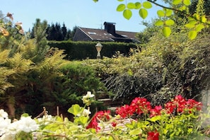 A garden with various plants and a house in the background. - Cuckoo House Premium (Titisee-Neustadt)
