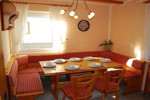 A dining area with a wooden table set for four, surrounded by red checkered benches. - Rolf Bauer on the ground floor (Konstanz)