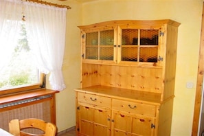 Ein Holzschrank mit mehreren Schubladen und einem gläsernen Oberteil.