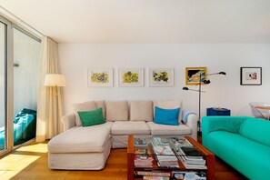 A modern living room with a sectional sofa, a coffee table with magazines, and artwork on the walls. - Bright & Modern T1 near Tagus River (Algés)