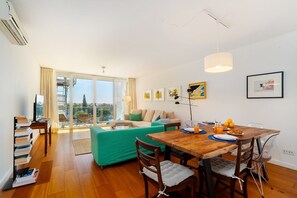 Un espace de vie moderne comprenant un coin repas, un canapé, une table avec des chaises et une vue dégagée grâce à de grandes fenêtres.