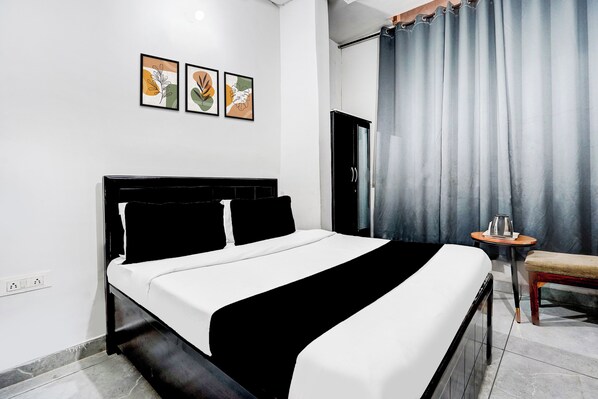 A hotel room with a bed, a small table, a chair, and a bathroom door.
