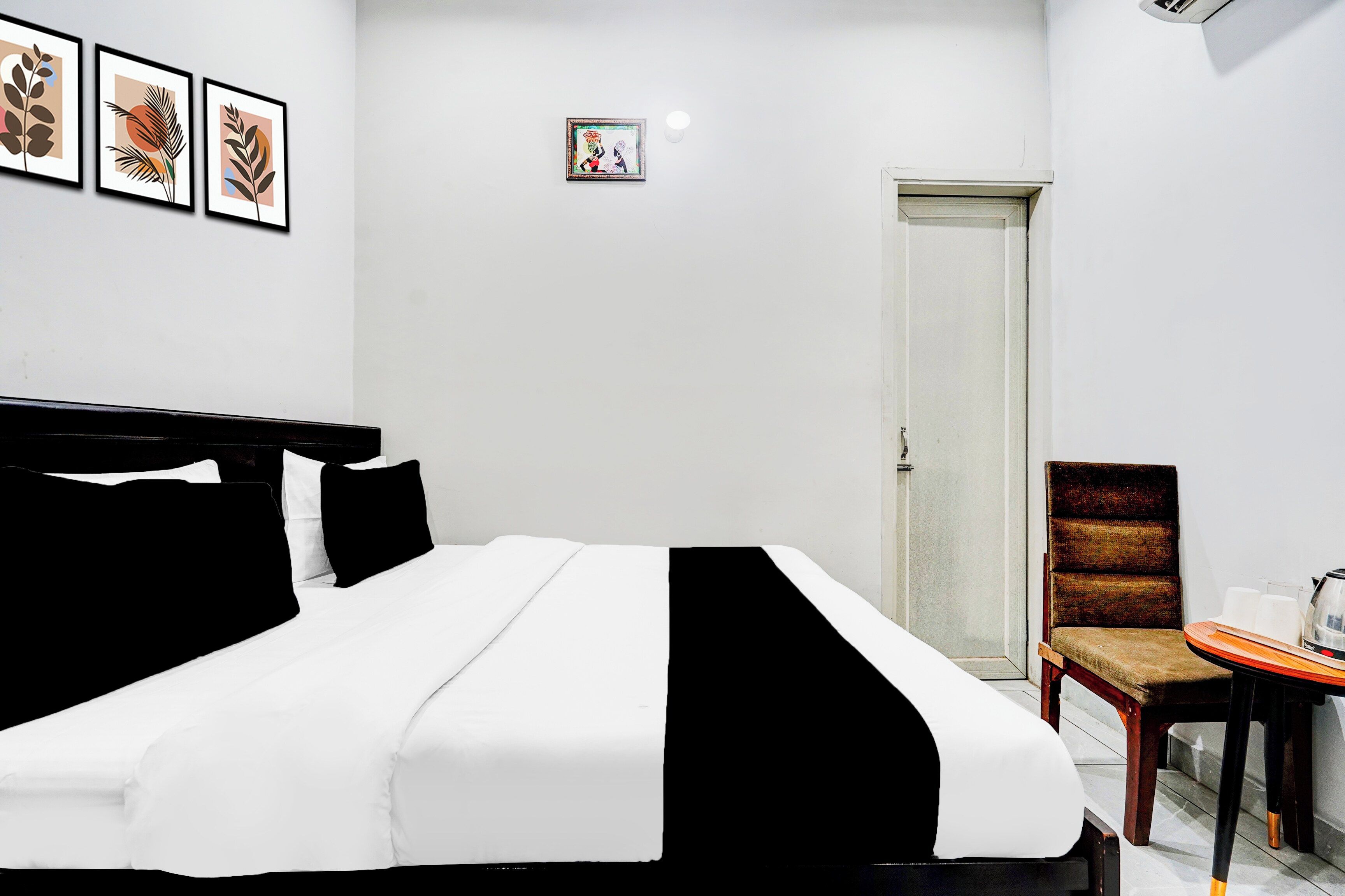 Une chambre d’hôtel avec un lit, une chaise, une petite table avec une bouilloire et une porte.
