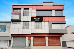 Un hotel de varios pisos con fachada moderna, que presenta un llamativo letrero con la palabra 'HOTEL' y un símbolo de servicio de la empresa.