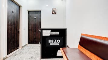 Zona de recepción de un hotel con mostrador, un banco y dos puertas.