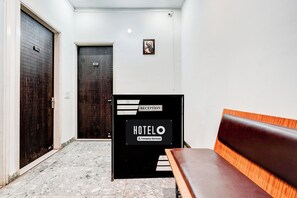 A hotel reception area with a reception desk, a bench, and two doors.