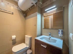 A bathroom with a toilet, sink, mirror, and a towel dispenser. - Studio 'Estudio con terraza a 100 m de la playa en Torrox Costa' (Torrox)