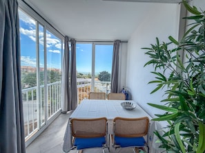 A balcony with a table and chairs, a view of the city, and a potted plant. - Studio 'Estudio con terraza a 100 m de la playa en Torrox Costa' (Torrox)