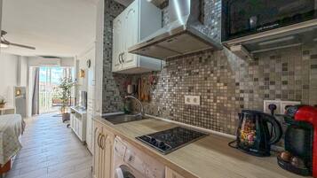 A modern kitchen with a built-in washing machine, a microwave, and a coffee machine.