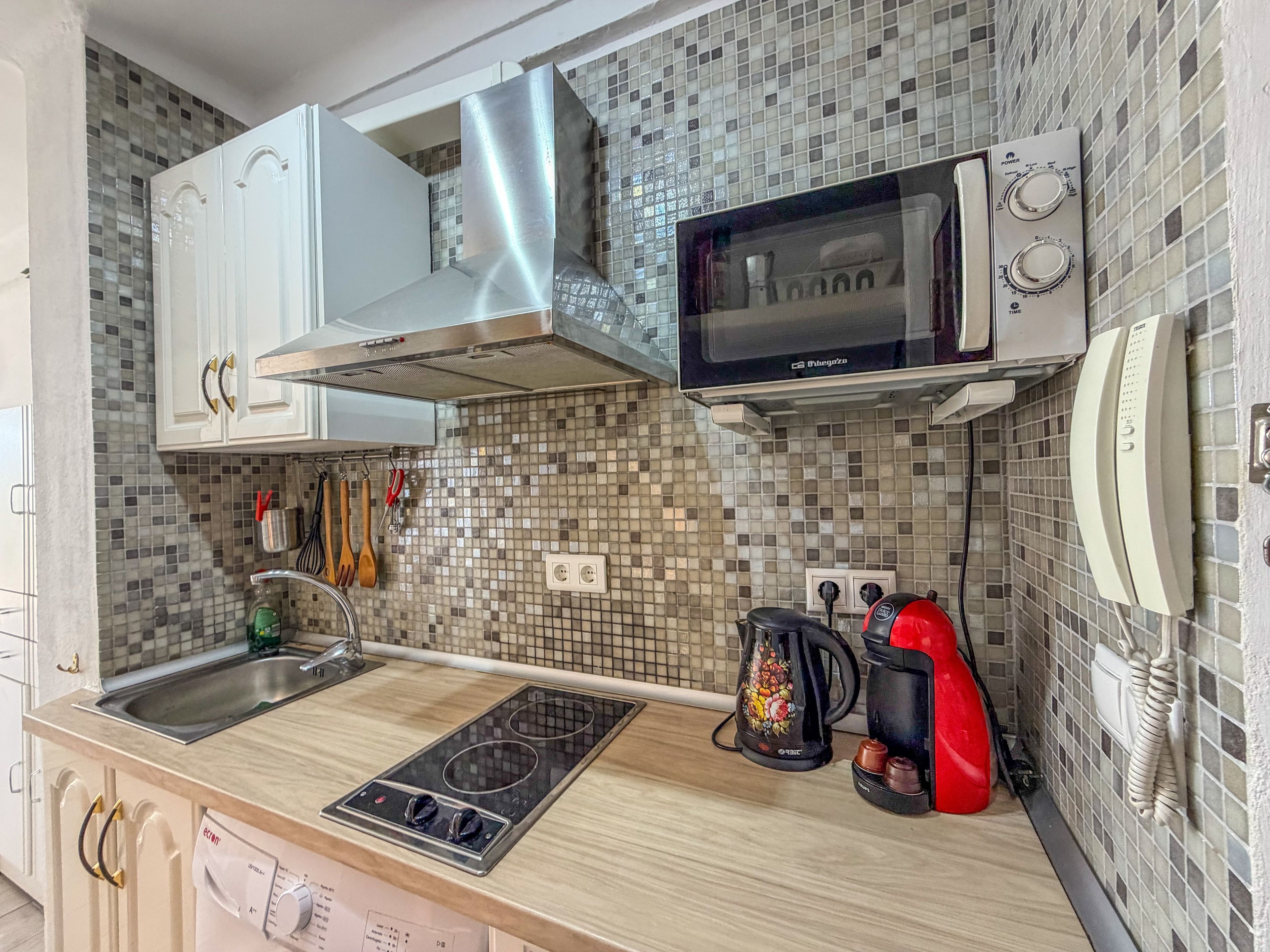 A kitchen with a microwave, stove, and a coffee maker.