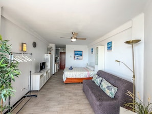 A compact room with a bed, a sofa, a desk with a computer, a wardrobe, and a ceiling fan. - Studio 'Estudio con terraza a 100 m de la playa en Torrox Costa' (Torrox)