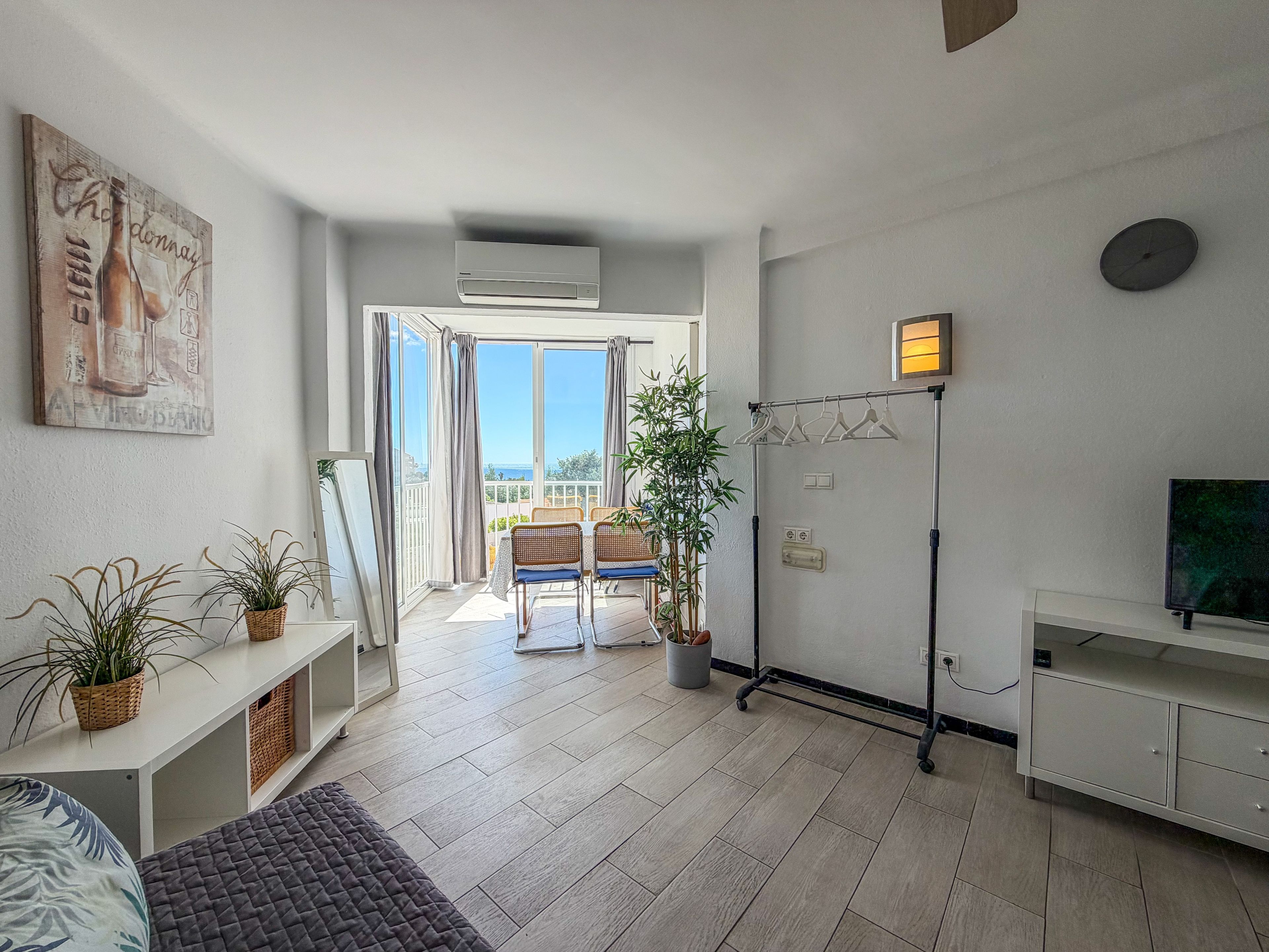 Un soggiorno moderno con balcone, televisione a schermo piatto e zona pranzo.