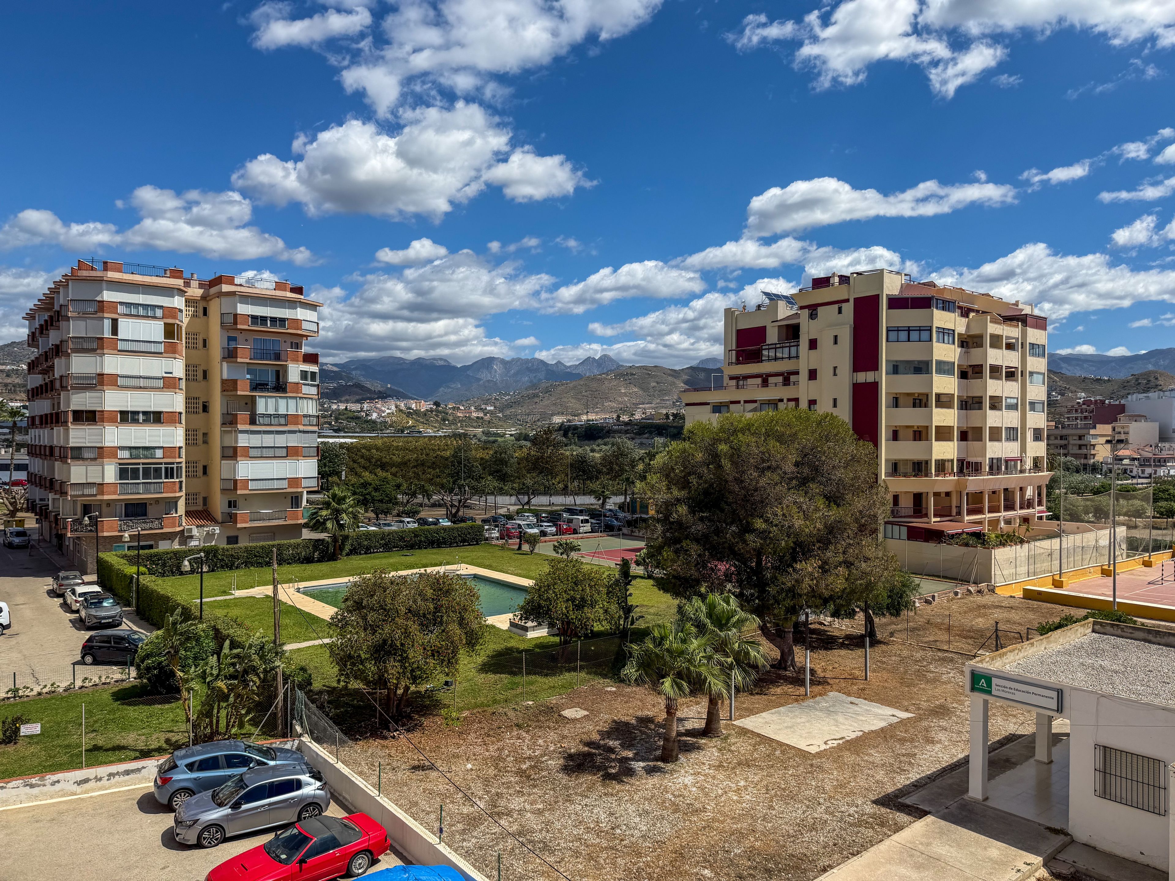 A residential area with multi-story buildings, a parking lot, and a small pool area.