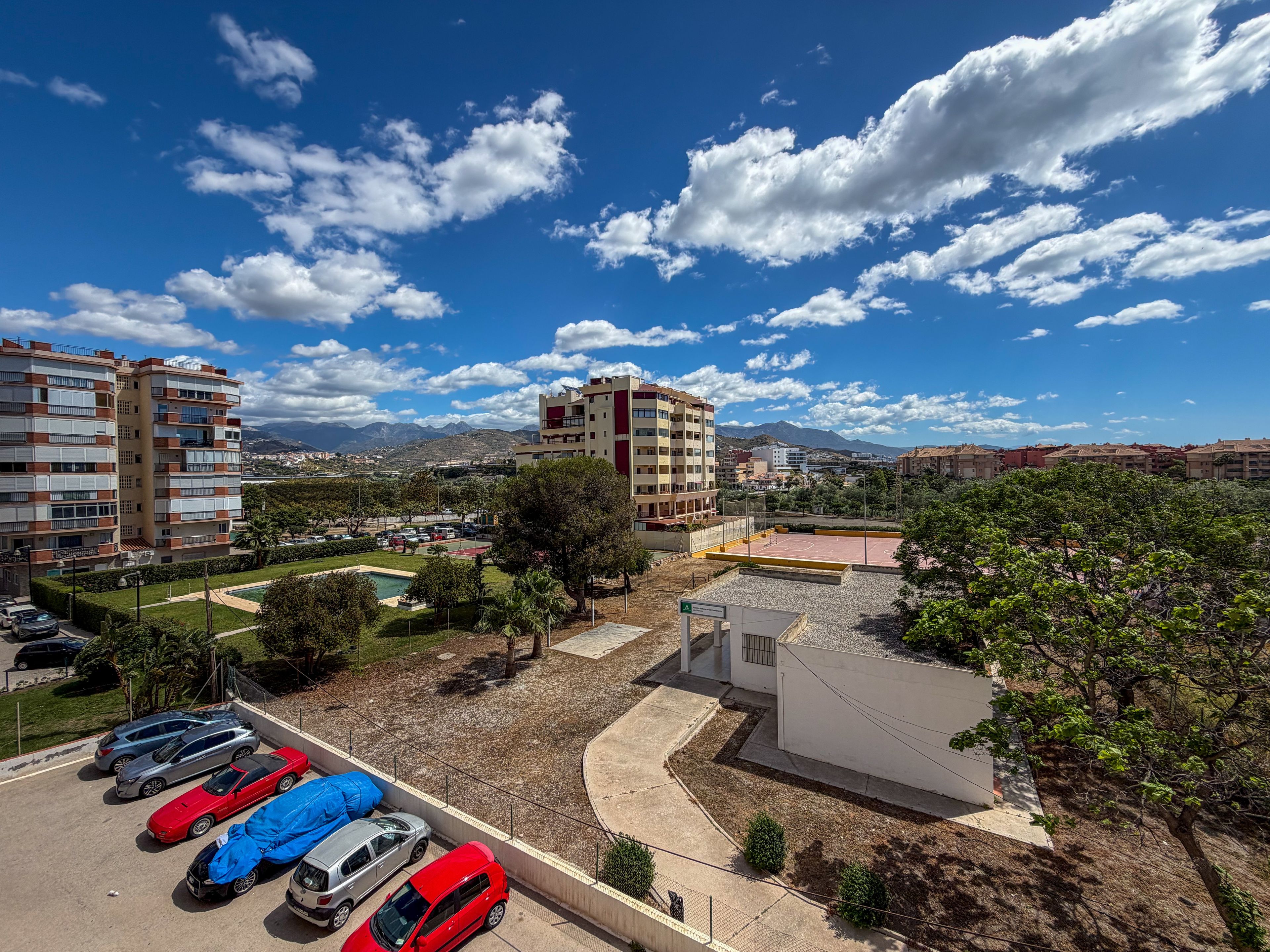 Un quartiere residenziale con edifici a più piani, un parcheggio e un campo da basket.