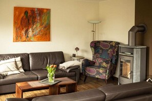 A living room with a sofa, armchair, and a fireplace. - Holiday home in Hooksiel with swimming pool (Hooksiel)