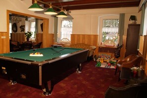 Una mesa de billar en una sala con paneles de madera, un área de comedor y un ventanal con vistas.