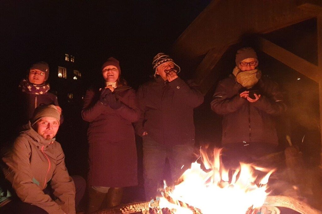 Un groupe de personnes s’est rassemblé autour d’un feu de camp au coucher du soleil.
