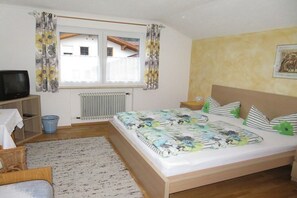 A bedroom with a bed, a television, a radiator, a window with curtains, a picture on the wall, and a small table. - Holiday apartment in Vils with swimming pool (Vils)