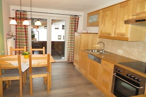 A kitchen with wooden cabinets, a built-in oven, and a dining area with a table and chairs. - Holiday apartment in Vils with swimming pool (Vils)