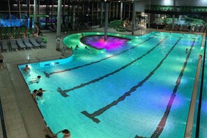 An indoor swimming pool with multiple lanes, lounge chairs, and a central hot tub area. - Holiday apartment in Vils with swimming pool (Vils)