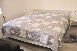 A bed with a quilted pattern, a bedside table with a lamp, and a furry rug on the floor. - Apartment in Kiel-Mitte with swimming pool (Kiel-Mitte)