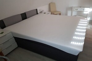 A modern hotel room with a large bed, a bedside table, a chair, and a small desk with drawers. - Mühlenblick 32 - Wohlgefahrt (Wittmund-Carolinensiel)