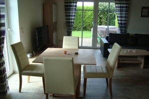 A dining area with a table and chairs, a television, and a sofa in a living room. - Mühlenblick 32 - Wohlgefahrt (Wittmund-Carolinensiel)