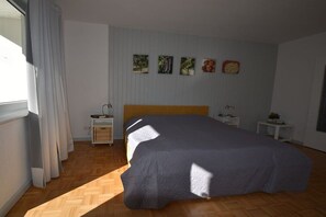 A bedroom with a bed, two bedside tables, a window with curtains, and wall art. - Holiday apartment in Kiel with swimming pool (Kiel)