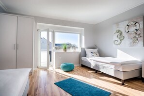 A bedroom with a bed, a window, a wardrobe, and a wall decoration. - Modern 3-room holiday apartment "Beach-Time" (Hörnum)