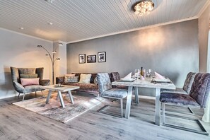 Ein modernes Wohnzimmer mit einer Sofagarnitur, einem Esstisch und einer Stehlampe.