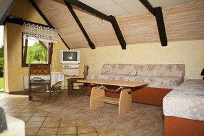 A cozy room with a sofa, a wooden table, a TV, and a chair. - Holiday home in Görlitz with swimming pool (Görlitz)