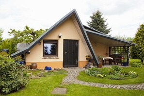 A single-story house with a sloped roof, a front door, and a small porch area with a table and chairs. - Holiday home in Görlitz with swimming pool (Görlitz)