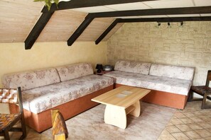 A cozy room with a sectional sofa, a wooden coffee table, and a brick wall. - Holiday home in Görlitz with swimming pool (Görlitz)