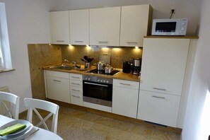 A compact kitchen with white cabinets, a microwave, a coffee maker, and a sink. - FH North Sea Feeling LD 113a (Hooksiel)