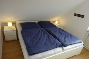 Ein Schlafzimmer mit einem Bett, zwei Nachttischen und einem Wandbild.