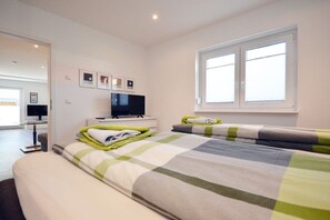 A hotel room with a bed, a television, a window, and a desk with a computer. - Holiday apartment with 1 bedroom (Norden)