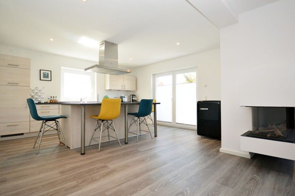 A modern kitchen with a central island, bar stools, and a built-in fireplace.