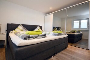 A modern bedroom with a large bed, a wardrobe, and a mirror. - Holiday apartment with 1 bedroom (Norden)