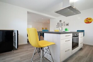 A modern kitchen with a bar area, a built-in oven, and a refrigerator. - Holiday apartment with 1 bedroom (Norden)