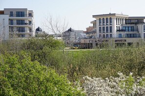 A residential area with modern buildings, a grassy field, and dense shrubbery. - Holiday apartment 5 - Flounder (Börgerende)