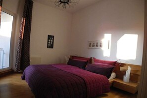 A bedroom with a bed, a bedside table, a window, and a wall with a picture. - Holiday apartment with 2 bedrooms (Wismar)