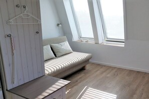 Ein Schlafzimmer mit einem Bett, einer Kommode und einem Fenster mit Jalousien.