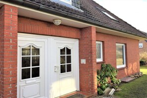 A brick house with a white front door, two windows, and a small garden. - Apartment with 1 bedroom (Wenningstedt\/Sylt)