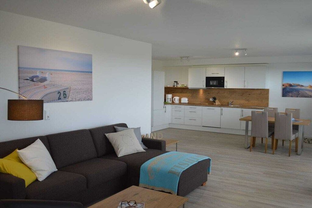 Un salon moderne comprenant un canapé, une table basse et un coin repas avec des chaises et une table.
